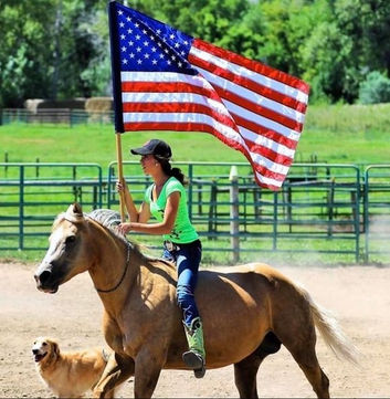 A young rider carrying the flag on a palomino with the family dog at Eclipse Ranch